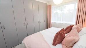 A bedroom with a bed, grey wardrobe, and curtains. - Maple House (Tadcaster)