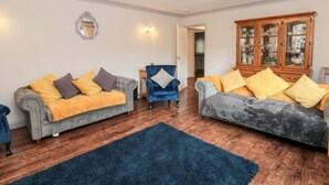 A living room with two grey sofas, a blue armchair, and a wooden cabinet.