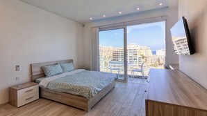 A bedroom with a bed, bedside table, and a TV mounted on the wall.