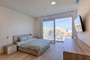 Un dormitorio con cama, mesita de noche y televisor montado en la pared.