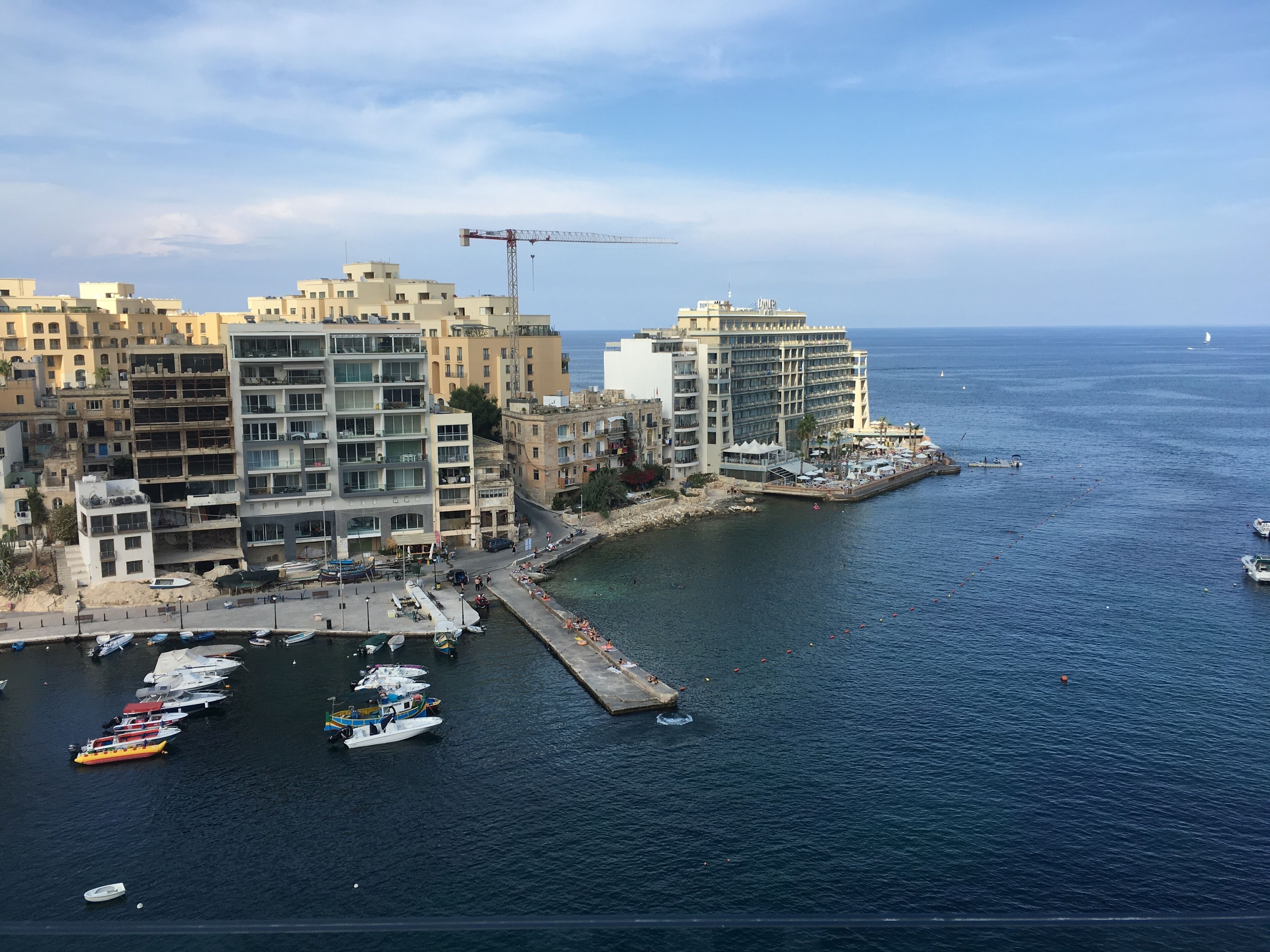 A coastal cityscape with a marina, including boats and a pier.