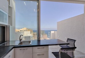 Una cocina moderna con un ventanal grande, un fregadero y una zona de comedor con una silla.