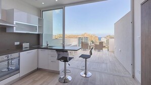 Una cocina moderna con un amplio ventanal, dos taburetes de bar y vistas a la ciudad.