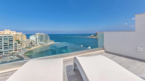 Un balcón con vista al mar y edificios.