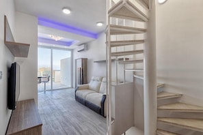 Un interior moderno con una escalera, un sofá y una televisión.