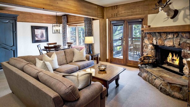 A cozy living room with a sectional sofa, a fireplace, and a stone accent wall. - Luxury Three Bedroom Suite with Mountain Views and Three Hot Tubs 3 Apartment Hotel by RedAwning (Park City)