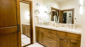 A modern bathroom with wooden cabinets, a large mirror, and a white countertop. - Deluxe King Room With Deck Hotel Room by RedAwning (Park City)