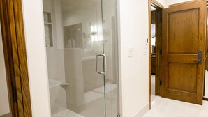 A glass-enclosed shower area with a metal handle, a wooden door, and a tiled floor. - Deluxe King Room With Deck Hotel Room by RedAwning (Park City)