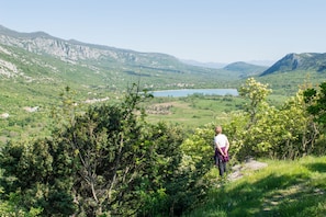 A person standing on a grassy hill overlooking a valley with a lake and mountains in the background. - Villa Cupido With Private Pool (Vinodol)