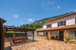 A courtyard with a pool, outdoor seating, and a stone wall. - Villa Cupido With Private Pool (Vinodol)