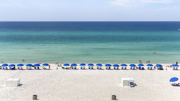 A beach with white sand, clear blue water, and blue umbrellas. - Ocean Ritz-501 4 Bedroom Condo by RedAwning (Panama City Beach)
