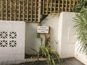 Un panneau indiquant un espace de stationnement réservé à un usage privé, une clôture en bois et un mur agrémenté d’un panneau décoratif.