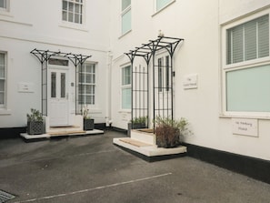 A white building with two entrances, each with a black metal gate and a small step leading up to the door. There are signs on the walls indicating "The Link" and "The White House."