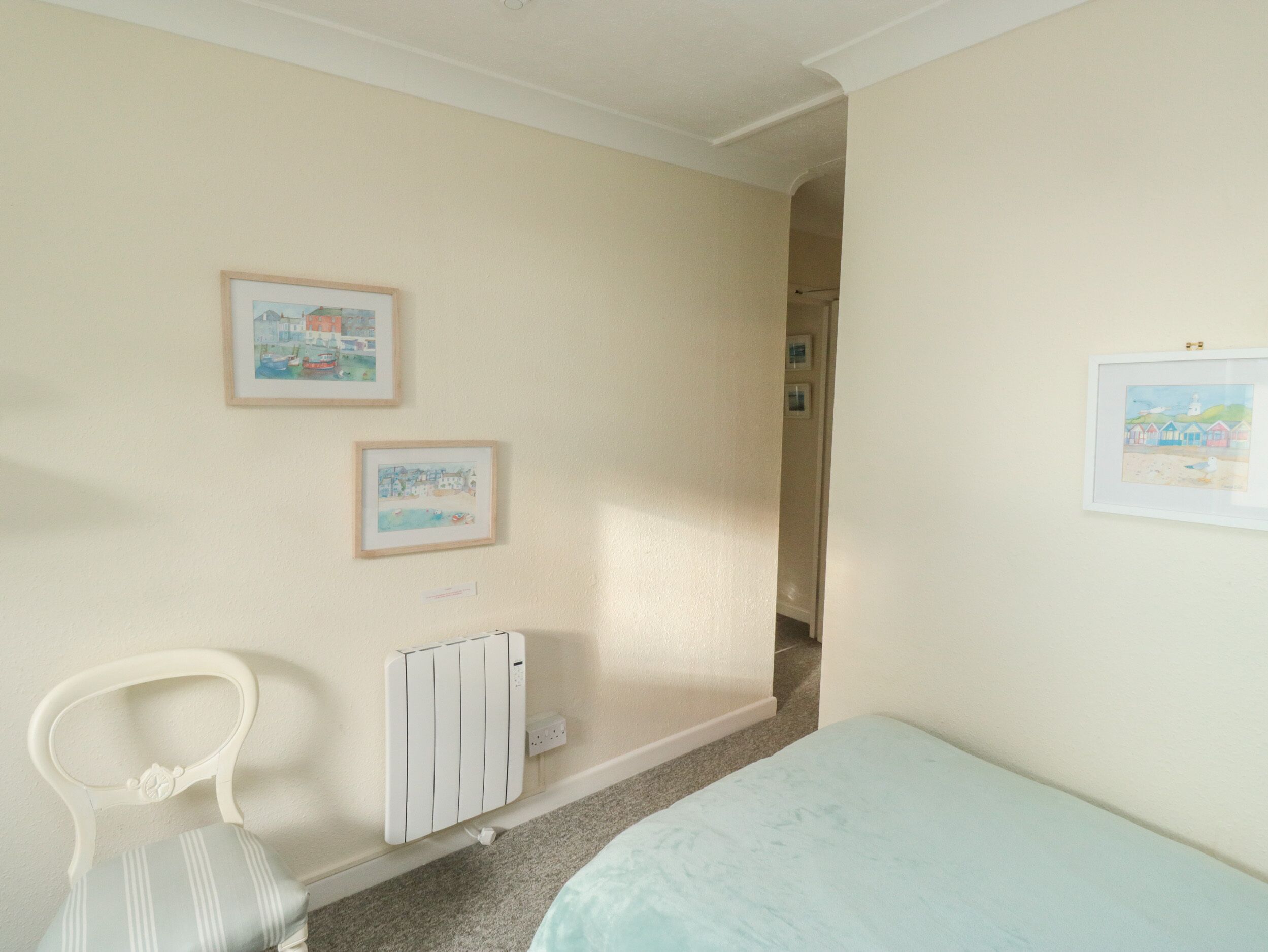 Un dormitorio con cama, una silla y dos cuadros en la pared.
