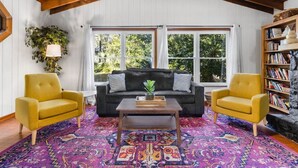 A cozy living room with a sofa, two armchairs, a coffee table, and a bookshelf. - Jeff GNV Home #1 · Renovated 3/2+ bonus, Heart of Gville, UF+Springs (Gainesville)