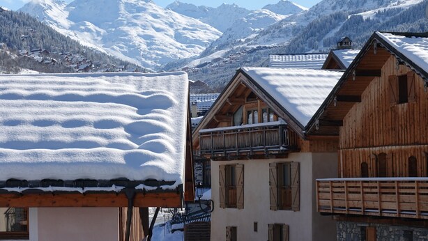 A mountain village with wooden houses, snow-covered roofs, and a backdrop of snow-capped mountains. - Tsaré Loft — Duplex 13 pers., Méribel (Les Allues)
