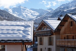 Un villaggio montano con case in legno, tetti imbiancati dalla neve e montagne innevate sullo sfondo.