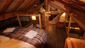 A cozy attic bedroom with a wooden ceiling, a plaid bedspread, and a view of the night sky. - Tsaré Loft — Duplex 13 pers., Méribel (Les Allues)