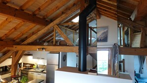 A rustic kitchen with wooden beams, a black chimney, and a view of the outdoors. - Tsaré Loft — Duplex 13 pers., Méribel (Les Allues)