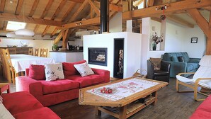 A cozy living room with a red sofa, a wooden coffee table, and a fireplace. - Tsaré Loft — Duplex 13 pers., Méribel (Les Allues)