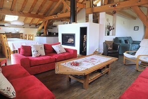 Un accogliente soggiorno con un divano rosso, un tavolino in legno e un caminetto.