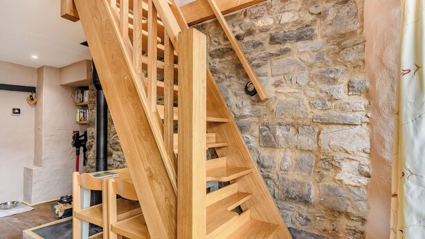 A wooden staircase with a stone wall background.