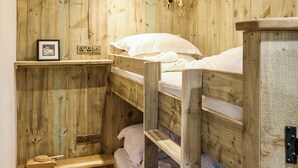Ein Schlafraum mit Etagenbetten, Holzwänden, einem Regal mit einem Bild und einem kleinen Holztisch.