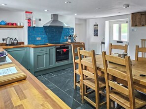 A modern kitchen with a blue backsplash, wooden cabinets, and a dining area with a wooden table and chairs.
