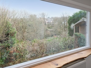 A window with a view of a garden, a wooden bench, and a white radiator.