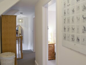 A hallway with a wooden door, a wicker basket, and a wall with framed animal illustrations.