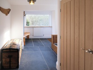 A hallway with a bench, a wooden chest, a radiator, a window, and a door.