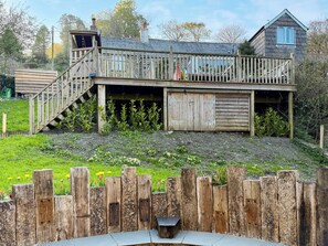 A wooden house with a deck, a staircase, and a small garden area.