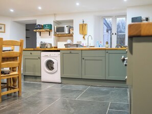 A compact kitchen with a washing machine, a microwave, and a sink. - 3 bedroom accommodation in Boscastle (Boscastle)