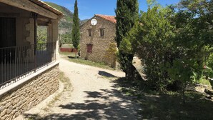 A rural road leading to a stone house with a tiled roof, surrounded by trees and a clear blue sky. - Charming 3-star farmhouse  (Reilhanette)