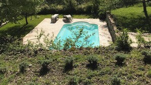A swimming pool surrounded by trees and a stone wall, with a clear view of the surrounding landscape. - Charming 3-star farmhouse  (Reilhanette)
