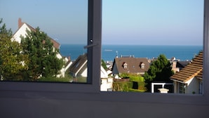 A view from a window overlooking a coastal area with houses and the sea.