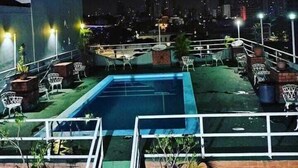 Une piscine sur le toit offrant une vue sur la ville la nuit.
