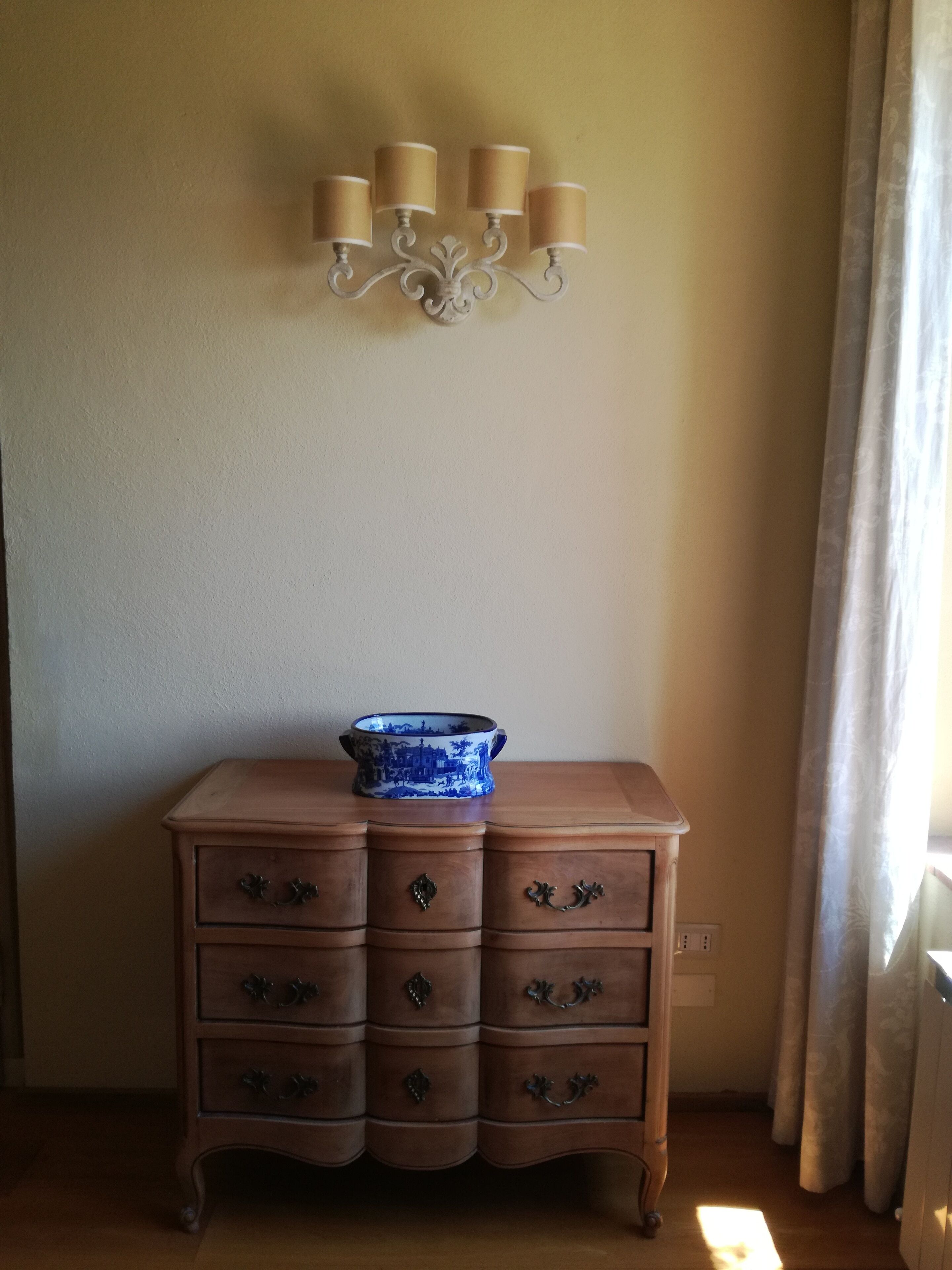 Une commode en bois avec six tiroirs, sur laquelle est posé un bol décoratif en céramique bleue et blanche.