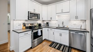 Una cocina moderna con armarios blancos, electrodomésticos de acero inoxidable y una encimera negra.