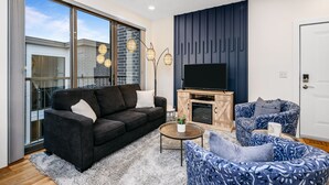 Una sala de estar moderna con un sofá, un sillón y un televisor sobre un mueble de madera.
