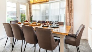 A dining room with a large table, chairs, and a chandelier.