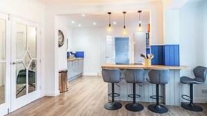 A modern kitchen with a central island, bar stools, and pendant lighting.