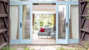 A doorway leading to a room with a sofa and chairs, a stone wall, and a view of greenery. - 1 bedroom accommodation in Old Sodbury, near Bristol (Old Sodbury, near Bristol)