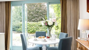 A dining area with a table set for four, chairs, a vase with flowers, and a view of a garden through a glass door. - 1 bedroom accommodation in Old Sodbury, near Bristol (Old Sodbury, near Bristol)