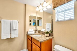 Bathroom features a granite countertop, white sink, and a mirror with a light fixture.