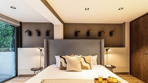 A modern hotel room with a large bed, bedside tables, a tray with breakfast, and a view of greenery outside. - Casa Horacio by Kukun (Mexico City)