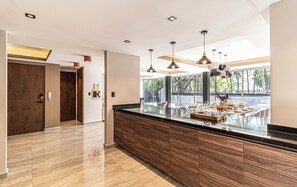 Una cocina moderna con encimera de mármol, armarios de madera, iluminación colgante y vistas al exterior.