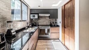 A modern kitchen with a built-in oven, microwave, and a large window. - Casa Horacio by Kukun (Mexico City)