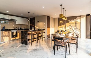 Een moderne keuken met een eetgedeelte, inclusief een centraal keukenblok, barstoelen en een muurschildering met tekst.
