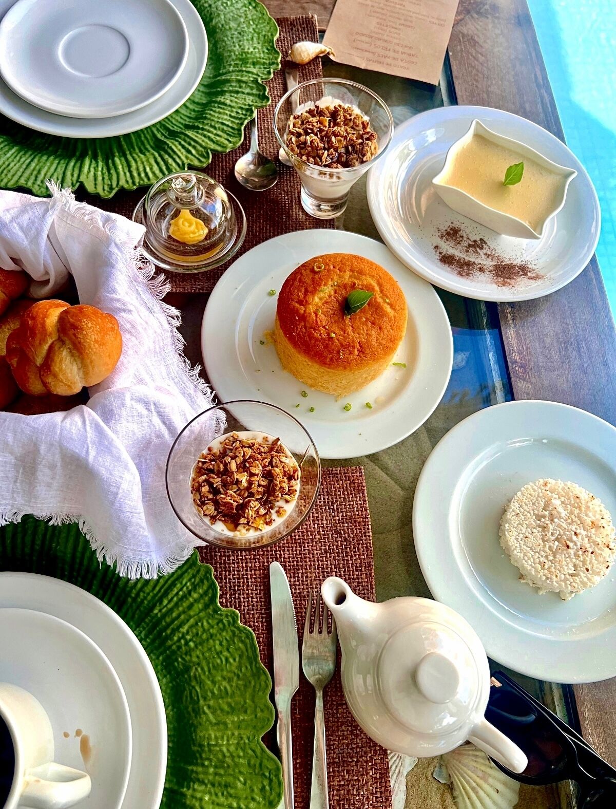 A table set with various dishes including a dessert, a bowl of granola, and a plate of rice.